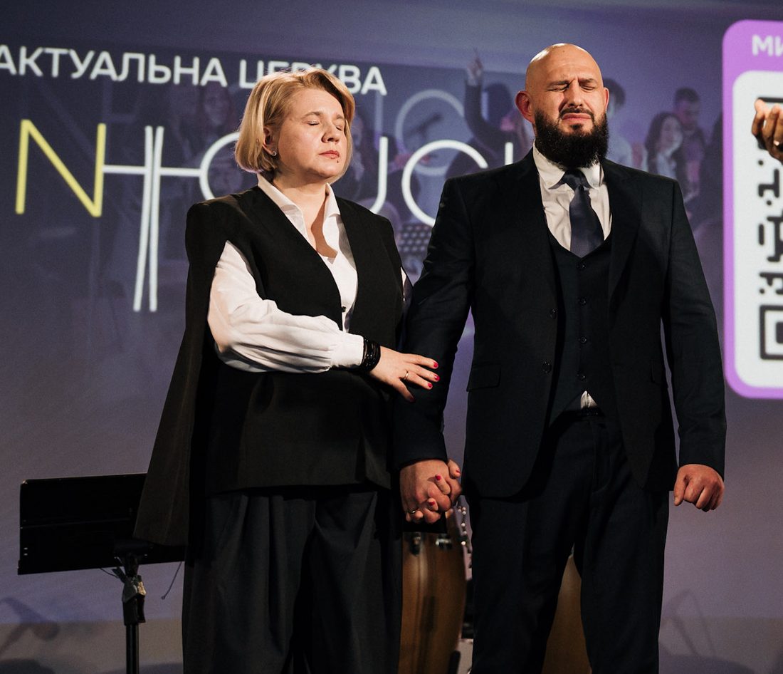 Пастори Дмитро та Олена Костирко під час молитви на служінні
